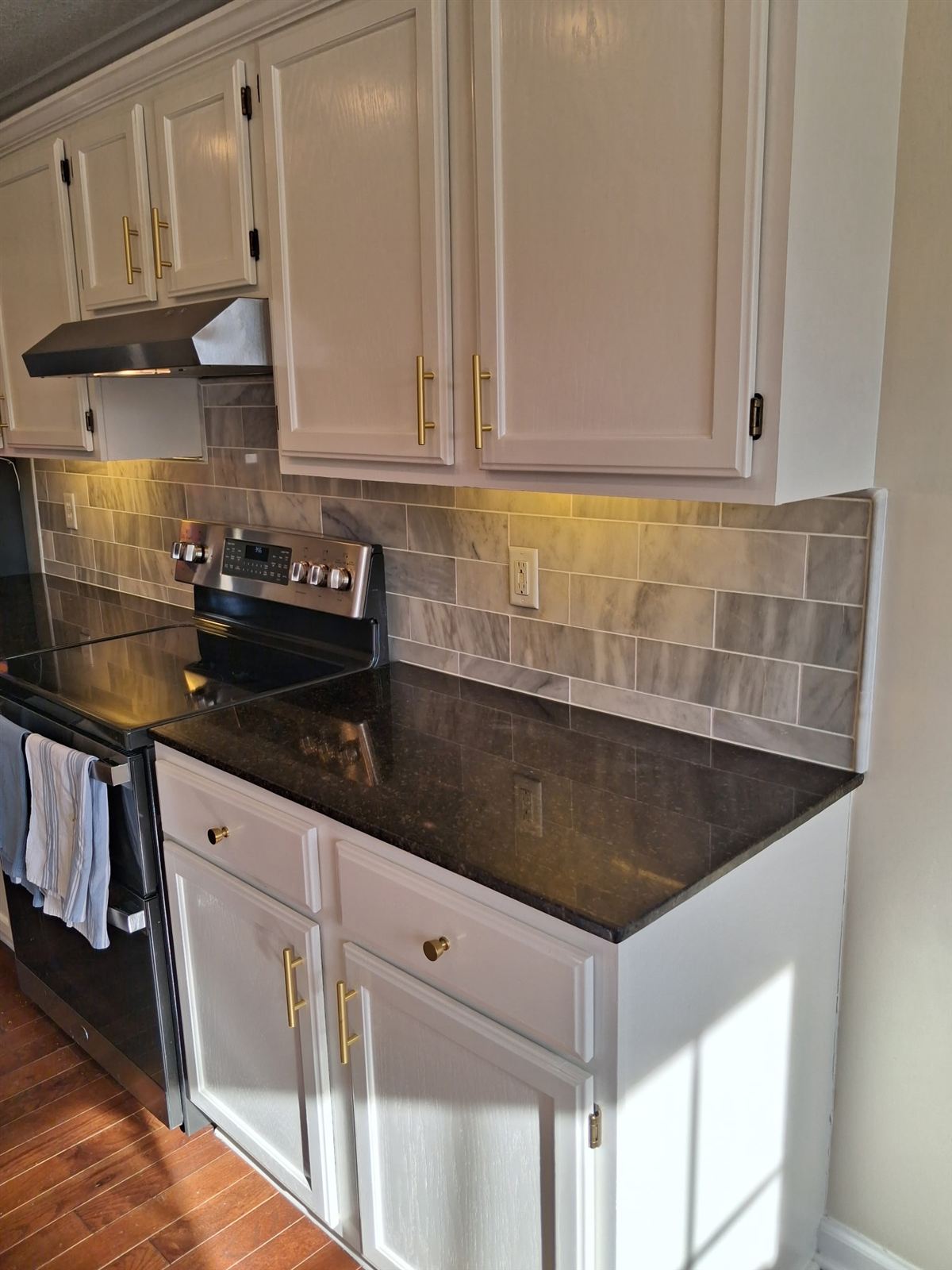 Kitchen with white painted cabinets, gold hardware and granite counters